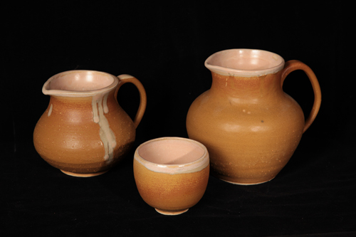 A pitcher, creamer, and cup glazed in cream and ash