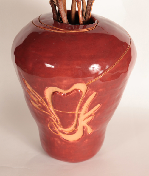 a vase with a swirly design on it in the shape of a heart with wings