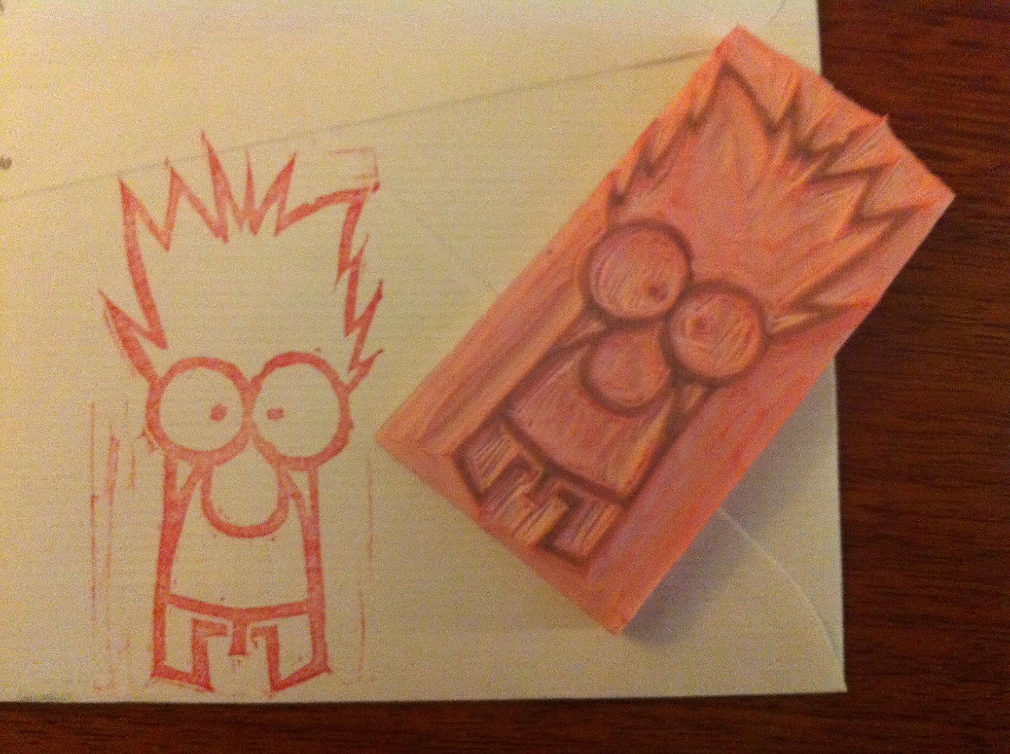 a hand carved pink rubber stamp of Beeker from the Muppets and a paper with the inked version in red