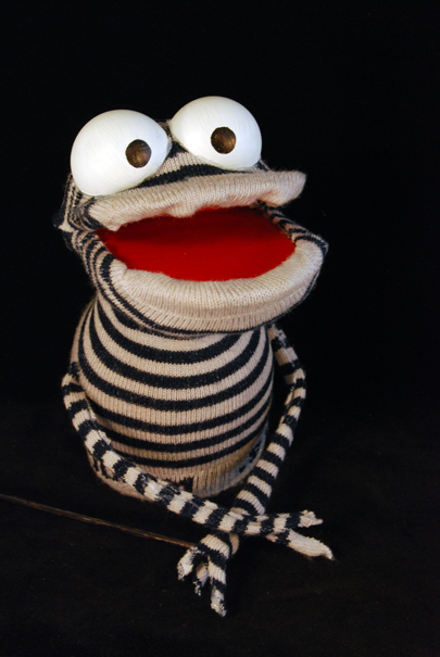 a striped muppet like sock puppet with a pronounced underbite