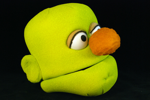 a bald green puppet head with a big orange nose